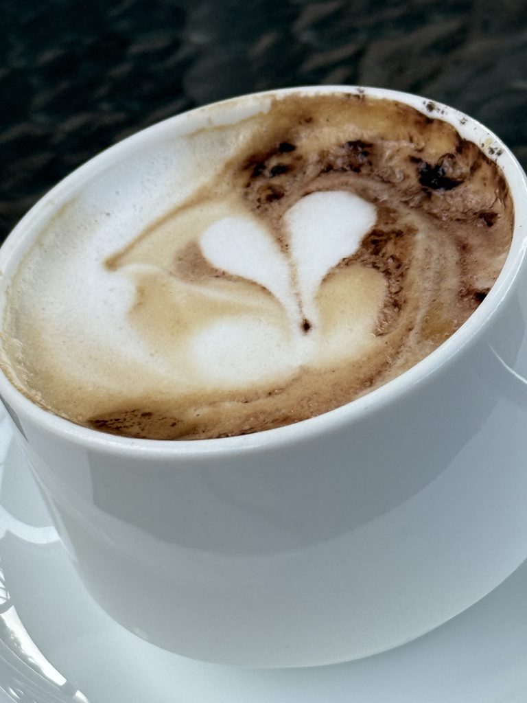 Close-up of a cup of cappuccino with a heart-shaped latte art design on top of the foam.